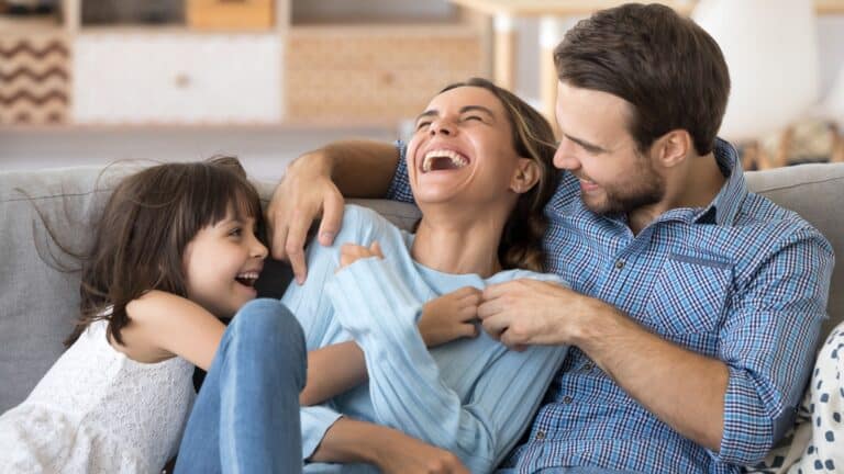 Family sitting on the couch embracing and laughing.