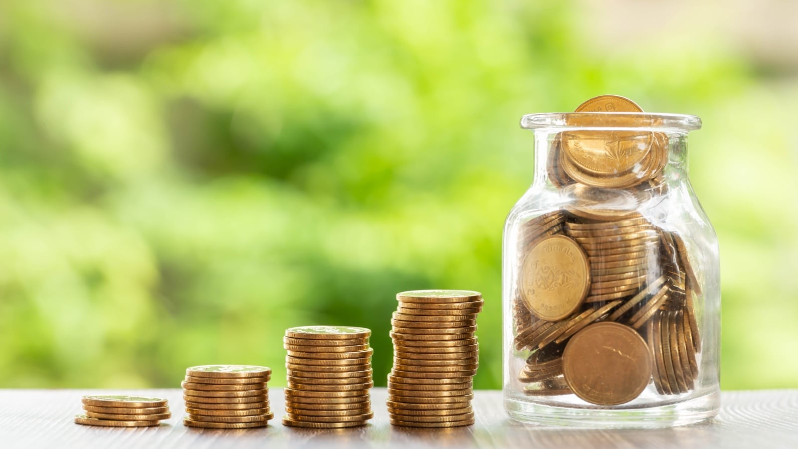 Coin stack money saving concept. Rows of coin on green bokeh background.